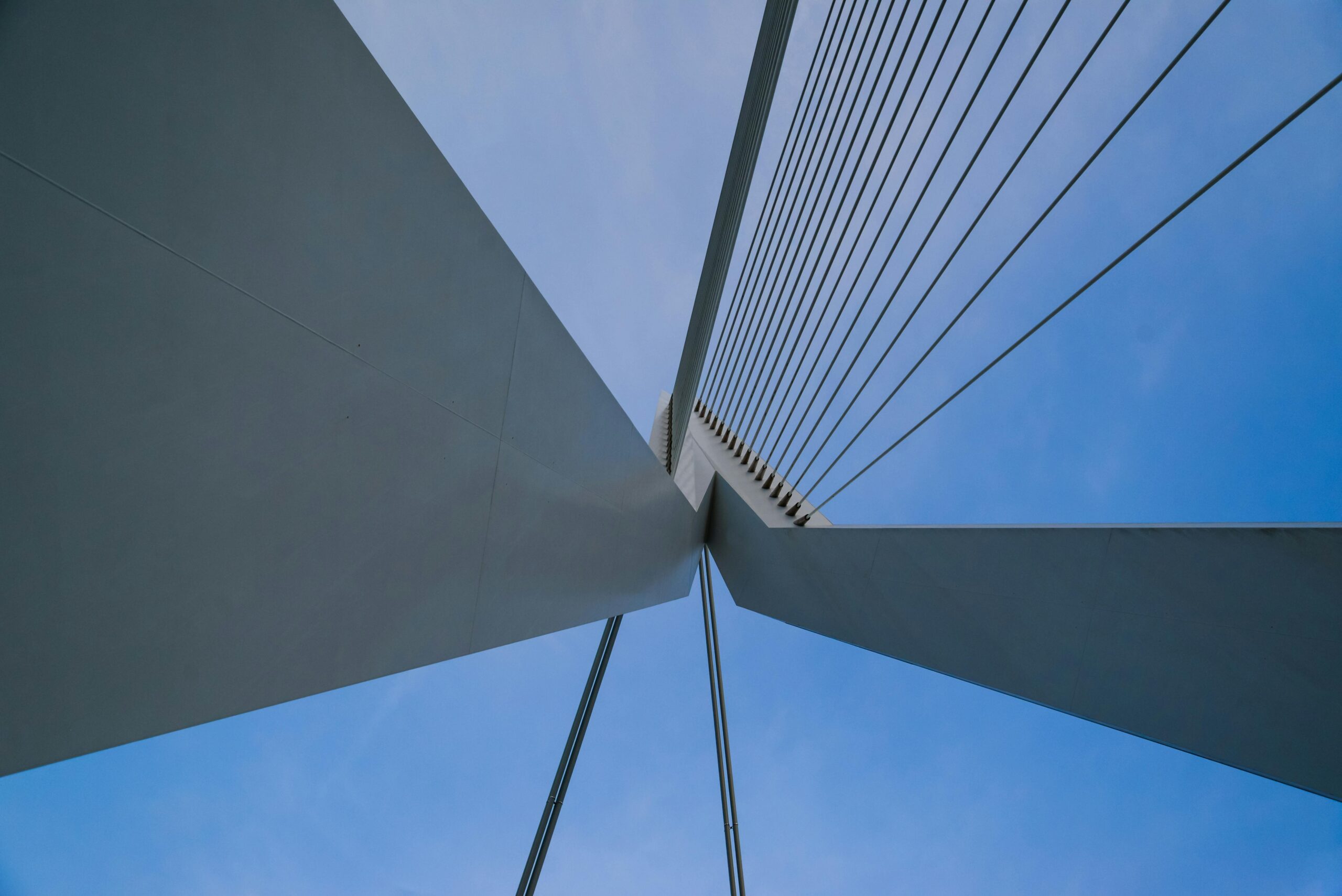 Low angle view of a modern architectural bridge design with cables against a clear blue sky.