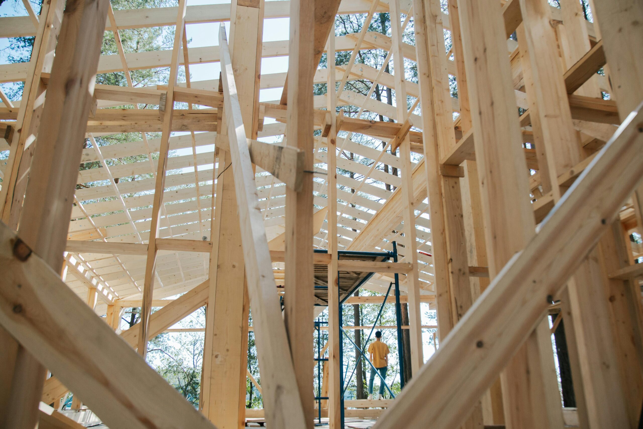 Interior view of wooden house frame under construction with visible scaffolding.